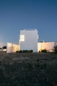 Modern minimalist white house at night with light on