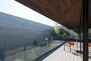 A modern patio featuring wooden elements and a glass barrier.