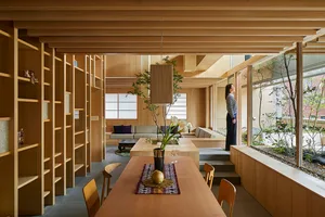 A modern residential space featuring a wood interior with a dining table, bookshelves, and a living area with a sofa and coff