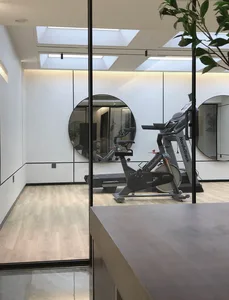 A modern gym room with minimalist design featuring a NordicTrack bike and treadmill.