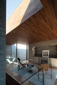 A modern living room with a wooden ceiling and floor, featuring contemporary furniture and a fireplace.