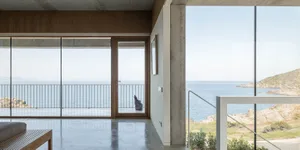 Interior view of a modern, minimalist residential space featuring concrete and glass materials.