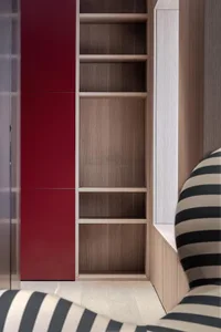 Modern, minimalist bookshelf with red doors and wooden shelves in an interior setting.