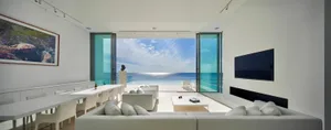 A modern living room featuring clear glass doors that open to reveal an ocean view.