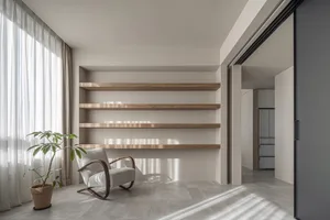 A modern living room with wooden shelves, a gray armchair, and a potted plant.