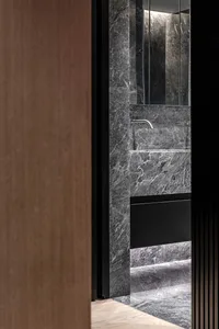 Modern minimalist bathroom with marble walls and black accents.