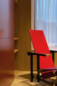 A minimalist red chair with black metal legs and yellow accents.