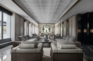 A spacious, modern residential interior featuring textured leather sofas, a center table with decorative items, and large win