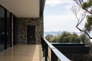 A modern residential setting featuring a stone and concrete exterior with a swimming pool overlooking a scenic landscape.