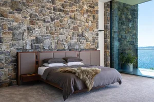 Modern bedroom featuring stone walls and concrete flooring