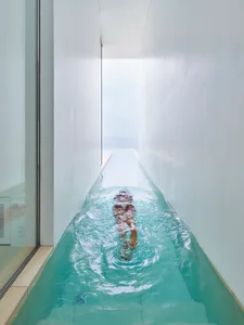 A minimalist, sleek, narrow swimming pool made entirely from concrete.