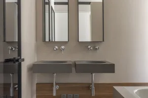 A modern industrial bathroom features a concrete countertop and minimalist design.