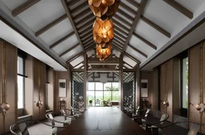 A spacious lounge with a high ceiling, wooden flooring, and large windows showcasing outdoor scenery.