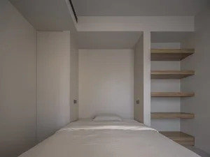 A minimalist bedroom featuring a simple bed with wooden walls.