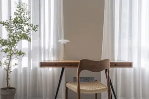 Modern minimalist home office with a wooden desk and white curtains.