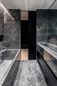 A modern bathroom featuring dark marble walls, countertops, and floor.