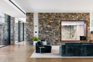 Modern living room with natural stone walls and dark velvet sofas