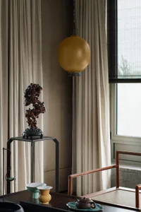 Modern minimalist living room with wood furniture, fabric curtains, and ceramic vases and teapot.