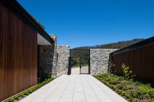 Modern house exterior featuring stone, concrete, and timber materials.