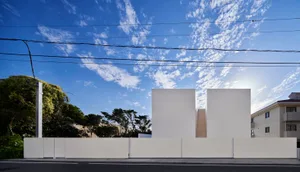 A minimalist urban residential building with a modern architectural design, featuring exposed concrete surfaces.
