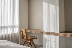 Minimalist bedroom featuring a wooden desk and white curtains