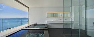 A modern bathroom with glass walls overlooking the ocean