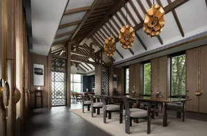 Modern dining room featuring laminated wood flooring, furniture, and accents, with a high-vaulted ceiling and large windows.