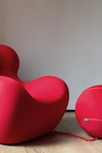 Two red, modern armchairs against a plain wall.