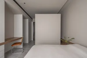 Minimalist bedroom with neutral-toned furniture and walls.