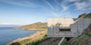 A minimalist vacation home featuring a concrete exterior with a small window.