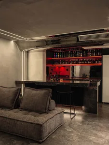 A modern industrial-style bar with black marble countertops and a black seating area.