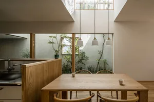 A minimalist dining and kitchen space featuring wooden furniture and a view of a garden.