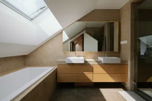 Modern minimalist bathroom with clean stone surfaces, double sink vanity, and skylight.