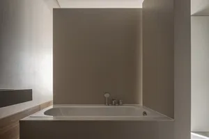 A modern minimalist bathroom featuring a bathtub with concrete walls.