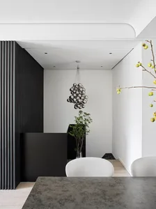 Modern dining room featuring a black wall panel and a metallic chandelier hanging from the ceiling.