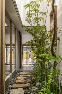 A modern residential entryway featuring natural stone pavers and green foliage.