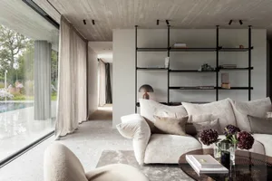 A modern living room featuring concrete elements and plush textiles.