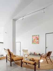 Modern living room with minimalist furniture, leather chairs, and a colorful abstract painting.