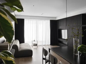 Modern living room featuring leather and glass furniture with minimalist design and wooden flooring.