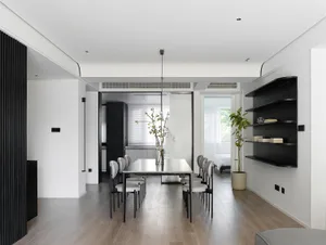 Modern minimalist living room with a wooden floor, white walls, and simple furniture arrangement.