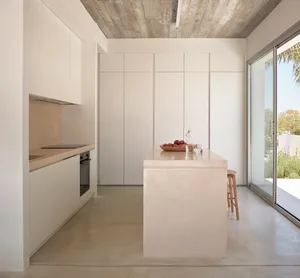 Modern minimalist kitchen with concrete island and white cabinets.