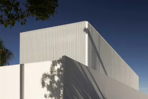 Modern white metal panel building exterior with a tree shadow.