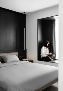A modern minimalist bedroom with a large bed featuring soft textiles and a dark wood headboard.