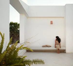 A minimalist outdoor space with clean lines, concrete walls, and a woman sitting on a low wall.