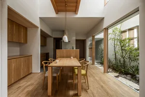A modern minimalist dining room with wooden furniture and a wooden floor.