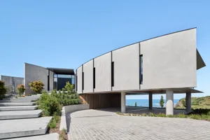 A modern residential building with concrete exterior and large glass windows.
