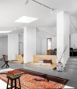 A minimalist living room features wooden benches and a large rug in a modern space.