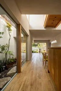 A minimalist residential interior featuring wood elements and a connection to an outdoor space.