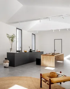 A modern residential kitchen featuring minimalist design, concrete countertops, wooden accents, and steel fixtures. Includes