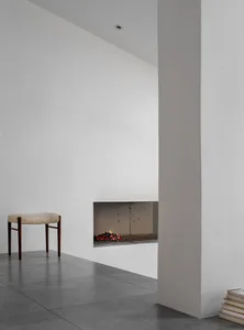 A minimalist living space featuring a corner fireplace with concrete walls and floor.
